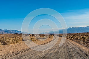 Dirt road in desert valley heading toward distant mountains