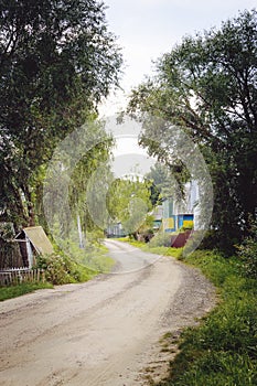 The dirt road and houses. Village street. Vertical photography