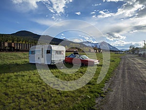 Dirt road leading the the Rockies, vintage camping trailer and car