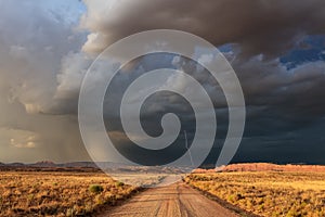 Dirt road leading to dark storm clouds and lightning