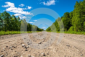 Dirt road leading to rural settlements. Country road and bright blue sky.