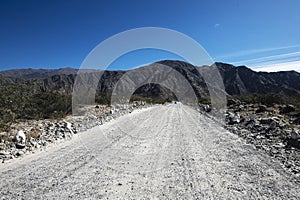 Dirt road perspective Tucuman Argentina valley calchaquies arid and dry with mountains rocks in Tafi del Valle conifers molles and photo