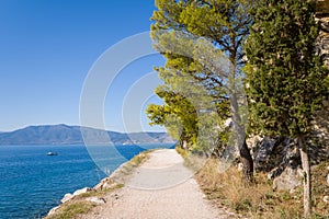 A dirt road on the rocky and arid but green coast, in Europe, Greece, Peloponnese, Argolis, Nafplion, Myrto seashore, in summer,