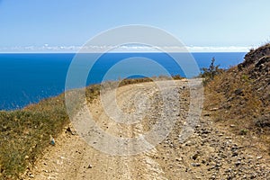 A dirt road running along a deserted mountainside on the seashore