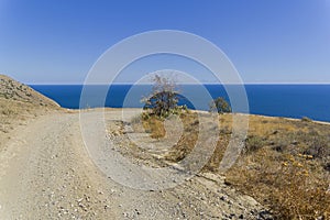 A dirt road running along a deserted mountainside on the seashore