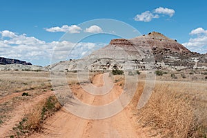 Dirt road to badlands hill and blue sky