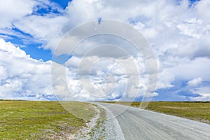 Dirt road to the horizon with clouds in the sky