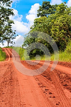 Dirt road track with bare earth red surface with visible vehicle tire tracks