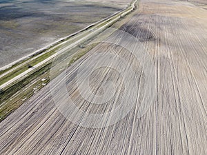 Dirt road between two plowed fields, aerial view. Agricultural land