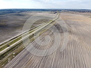 Dirt road between two plowed fields, aerial view. Agricultural land