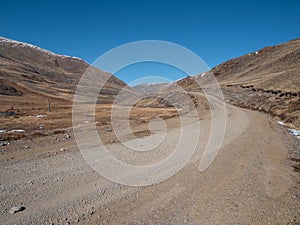 Dirt road uphill. Dangerous narrow dirt mountain road through the hills to a high-altitude village. Altai region