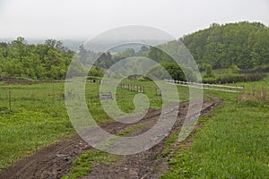 Dirt rural road among the green hills at countryside