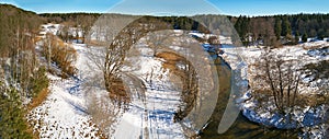 Dirt rural road, wood, ice and snow panorama. Islach river aerial view, Belarus