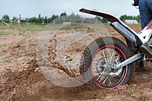 Dirt and sand fly from under rotating wheel of offroad motorcycle, action image, copy space