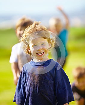 Dirt, smile and face of child for games by grass, lawn and outdoor playing outside with happiness in nature. Boy