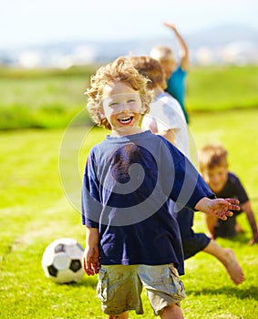 Dirt, smile and portrait of child for soccer by grass, lawn and outdoor playing with happiness in nature. Boy, freedom