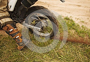 Dirtbike rear wheel in motion with dirt track on grass.