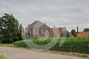 Dirtroad along green cornfields and gentleman`s farm in the Flemish countryside