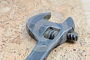 Dirty adjustable wrench on a cork background. Old spanner