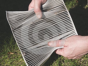 Dirty air filter for the cabin in the hands of man, close up. Changing the car air filter