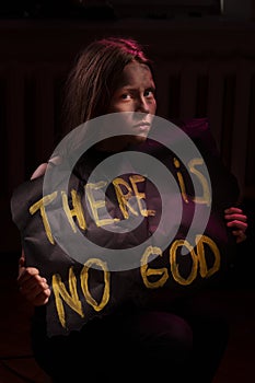 Dirty atheist teen girl holding a banner with the inscription photo