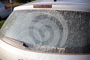 Dirty back glass on car from unclean rain with sand