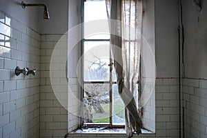 A dirty bathroom in an abandoned house of Chernobyl. Broken window with old curtain, feeling of depression in a crackhouse