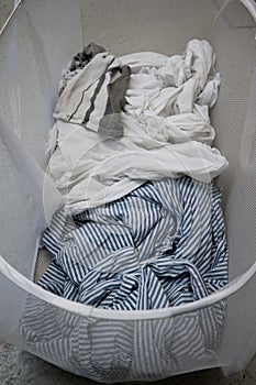 Dirty bedding inside fabric mesh laundry basket top view