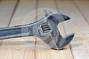 Dirty adjustable wrench on a wooden background. Old spanner