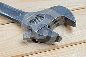 Dirty adjustable wrench on a wooden background. Old spanner