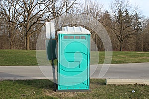 A Dirty, Blue Portable Toilet in a Park, nasty looking place to go to the bathroom photo