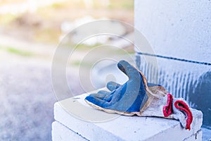 A dirty blue rubberized construction glove lies on a construction site