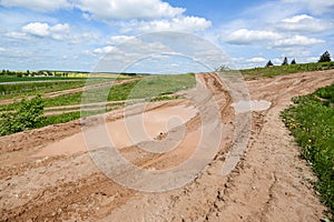 Dirty broken rural road with deep tire tracks