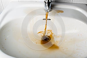 Dirty brown water running into a sink