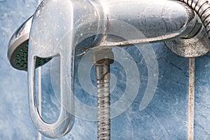 Dirty calcified shower mixer tap, faucet with limescale on it, close up