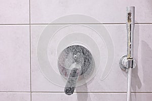 Dirty calcified shower mixer tap, faucet with limescale on it, plaque from hard water, Chrome plated shower, close up