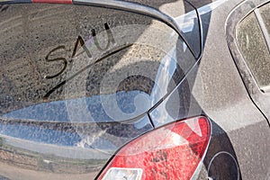 Dirty car with the german word for sow on the rear window