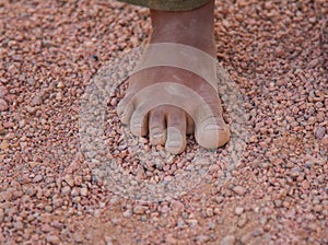 Dirty children`s foot is in the desert sand