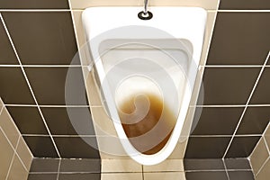 Dirty clogged urinal with water in the toilet of a restaurant. Disinfection and hygiene in toilets of public buildings