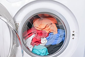 Dirty clothes are inside the washing machine. Automatic washer with open door. Erasing home t-shirts