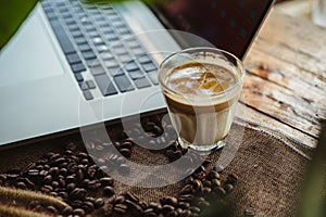 Dirty coffee cup and coffee beans with laptop computer