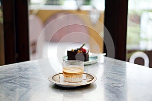 Dirty Coffee - A glass of espresso shot mixed with cold fresh milk served with chocolate cake on blurred background.