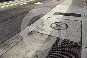 Dirty concrete and brick sidewalk alongside a street, turn lane arrow and streetcar rails, metal grate and manhole, Georgia USA