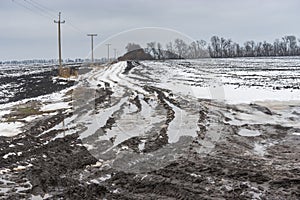 Dirty country road between agricultural fields in central Ukraine at gloomy winter day