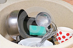 dirty dishes and kitchen utensils in a sink. messy kitchen. cluttered sink. daily routine, chores and housekeeping