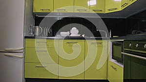 Dirty dishes lying on the table. Dishwasher automatic electric. Stylish modern Built In Kitchen Appliances in green