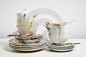 Dirty dishes pile needing washing up on white background