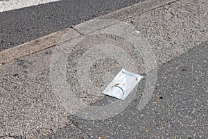 A dirty disposable face mask discarded on a road in England