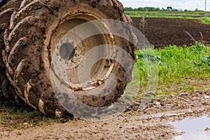 dirty double wheel of a big agriculture tractor on dirt road at summer day