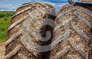 dirty double wheels of agriculture tractor at sunny summer day